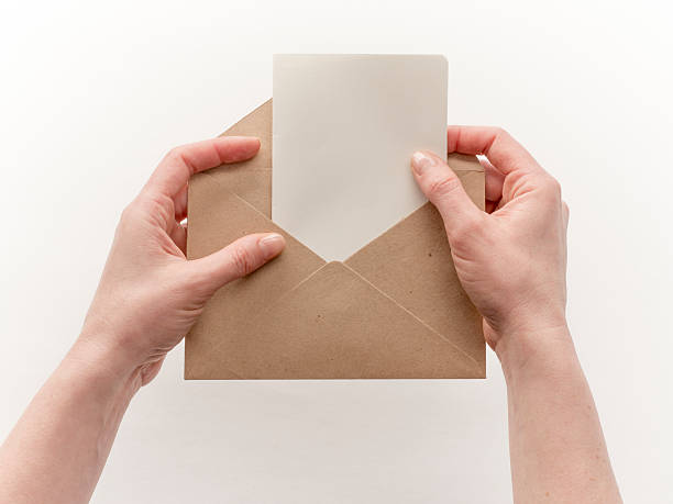 istock Female hand holding craft envelope, isolated on white 528954374