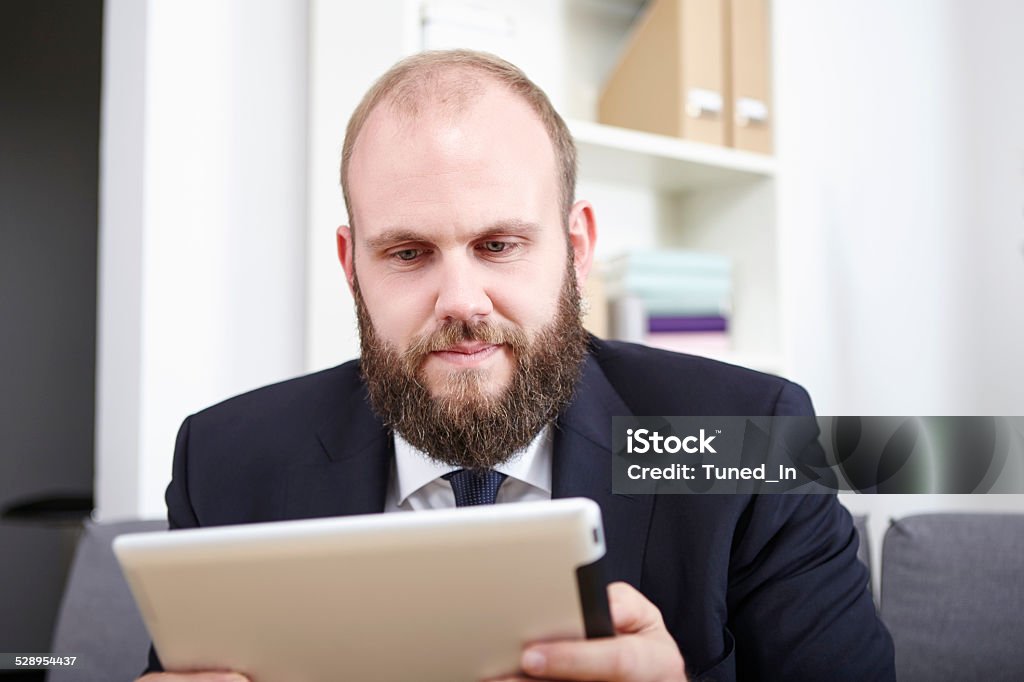 Businessman reads something on his tablet computer Adult Stock Photo