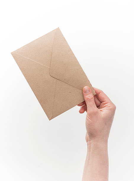 istock Female hand holding craft envelope, isolated on white 528954664