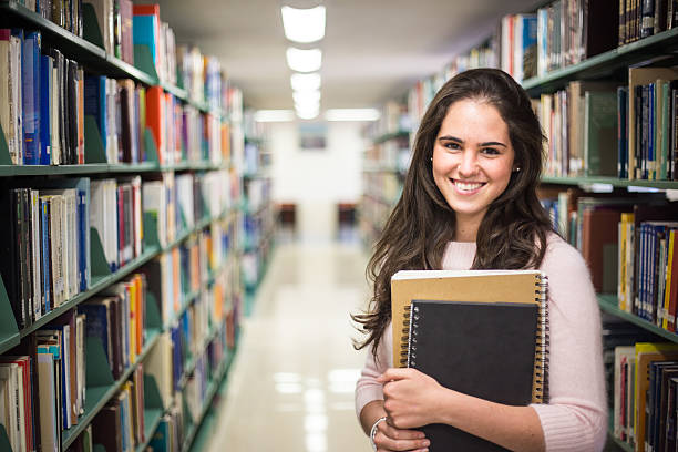 In the library - pretty female student with books In the library - pretty female student with books working in a high school library. masters degree photos stock pictures, royalty-free photos & images