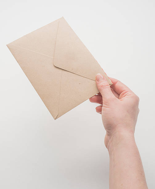 istock Female hand holding craft envelope, isolated on white 528954770
