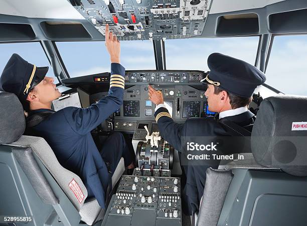 Pilot Pushing Button In Airplane Cockpit With Copilot Stock Photo - Download Image Now