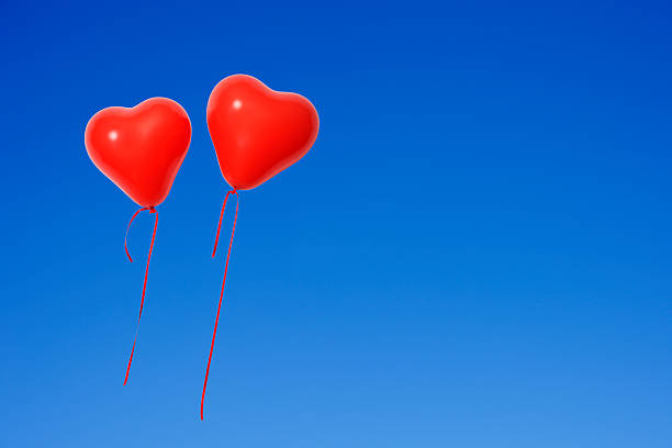 White and red balloons flying high up towards the blue sky with veil clouds