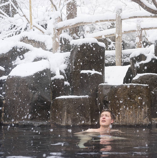 istock Man enjoying soak in winter hot spring during snow 528960867