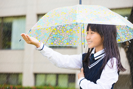 pretty  student girl holding umbrella  in the rain