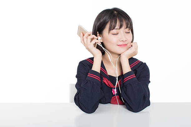 girl sitting in the desk in front, using a mobile phone to listen to music