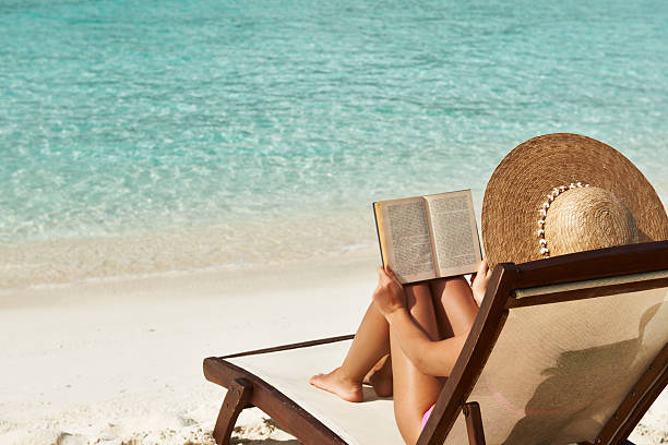 Young woman reading a book at beach stock photo