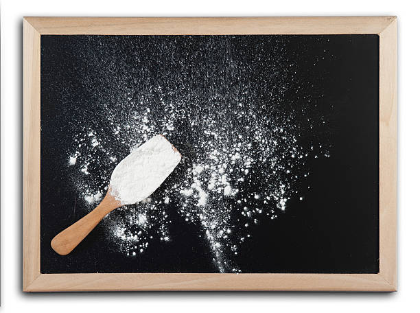 White flour and spoon on blackboard with wooden bamboo frame