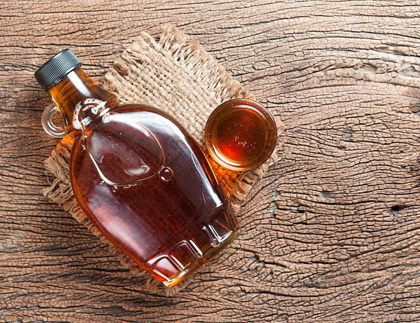 maple syrup in glass bottle on wooden table maple syrup in glass bottle on wooden table maple syrup stock pictures, royalty-free photos & images