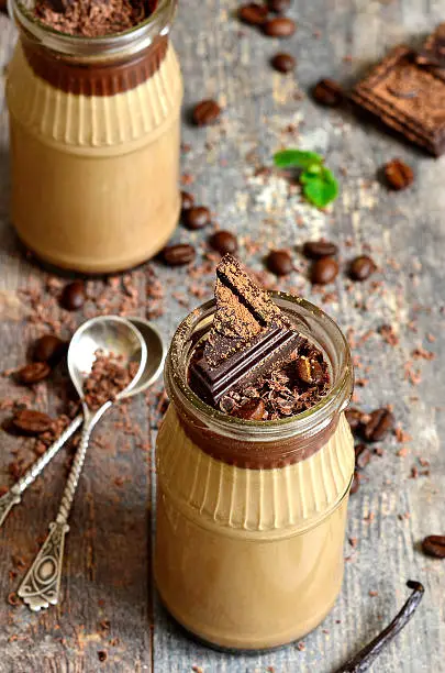 Chocolate coffee pannacotta in a glass jar on rustic background.