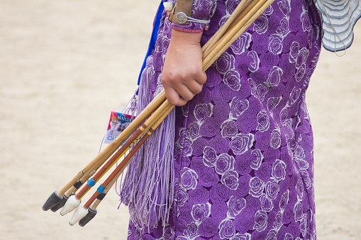 Close up shot of a Mongolian female archer wearing traditional clothing with beautiful purple pattern whilst holding her arrows ready for the games.