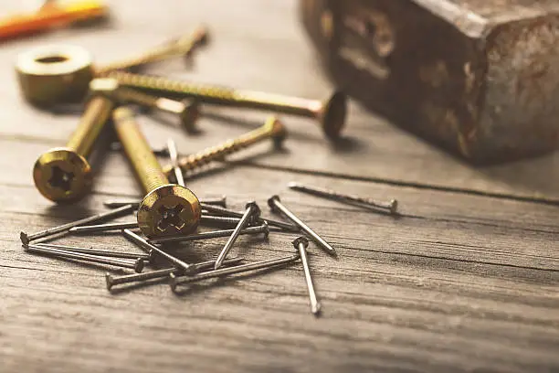 Photo of cross head bolt screws thread with nails and hammer