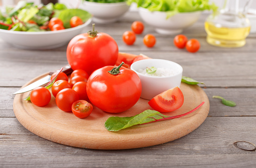 Fresh tomatoes on a wooden chopping board on the wooden table in a rustic kitchen