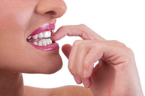 Woman bites her nails care Beautiful young woman bites her nails. Sha has perfect skin and white teeth, isolated on a white background. Chew Your Nails  stock pictures, royalty-free photos & images