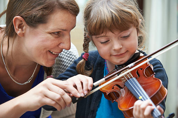 profesor ayudando a joven mujer alumno en clase de violín - violin family fotografías e imágenes de stock