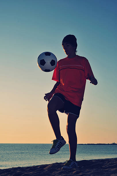 istock Boy playing football on beach 528983951