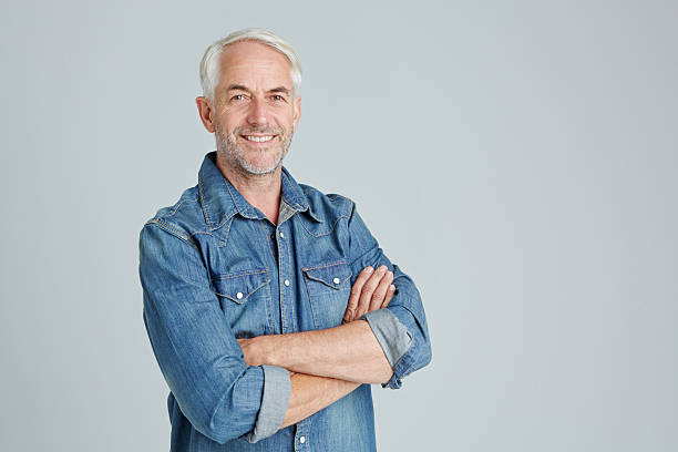He's a laid-back sort of guy Studio portrait of a handsome mature man standing with his arms crossed waist up stock pictures, royalty-free photos & images