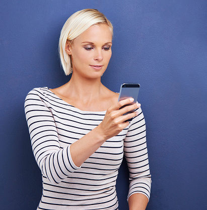 Studio shot of a beautiful young woman using her mobile phone