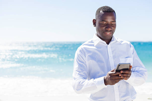 istock African businessman sending a message on the beach. 528985351
