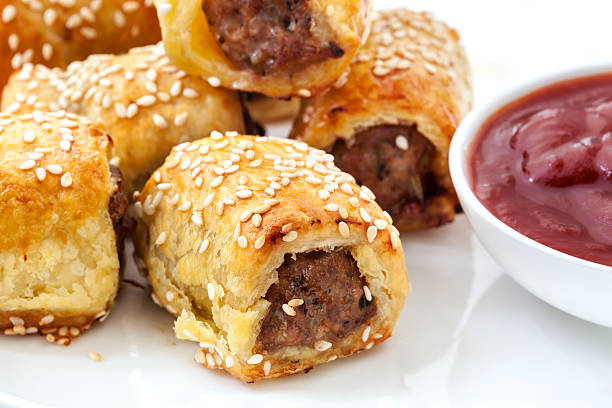 Sausage Rolls Sausage rolls with tomato sauce or ketchup.  Puff pastry sprinkled with sesame seeds. sausage roll stock pictures, royalty-free photos & images