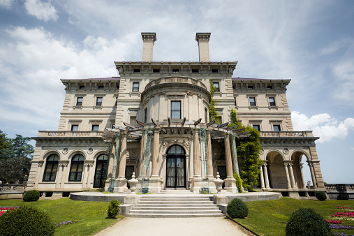 Newport, United States - August 10, 2014: A woman is seen on the back patio of The Breakers, a mansion along the historic Cliff Walk in Newport. The Breakers was built as the Newport summer home of Cornelius Vanderbilt II and was completed in 1895.