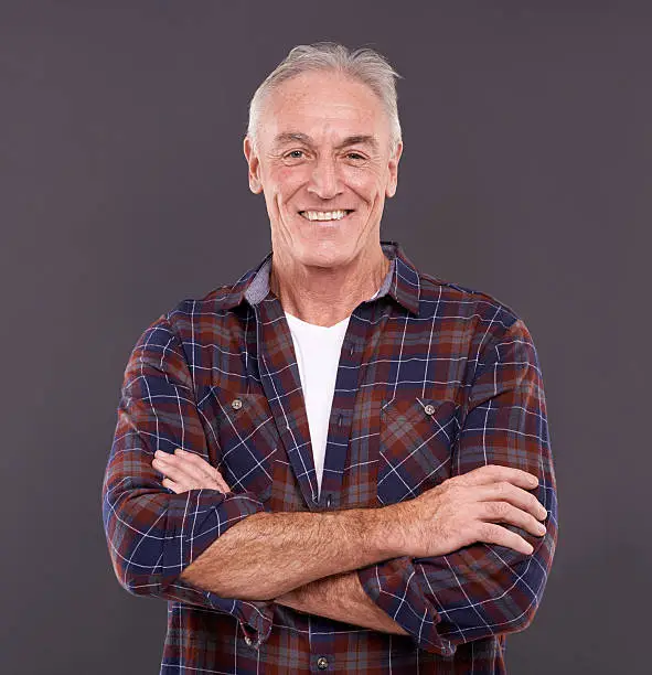 Studio portrait of a confident elderly man against a gray background