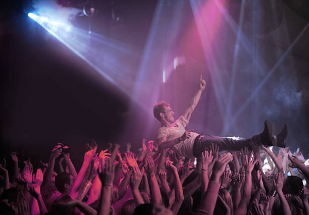 Surfing on a wave of praise A stage diver being carried across the audience at a rock concert mosh pit stock pictures, royalty-free photos & images