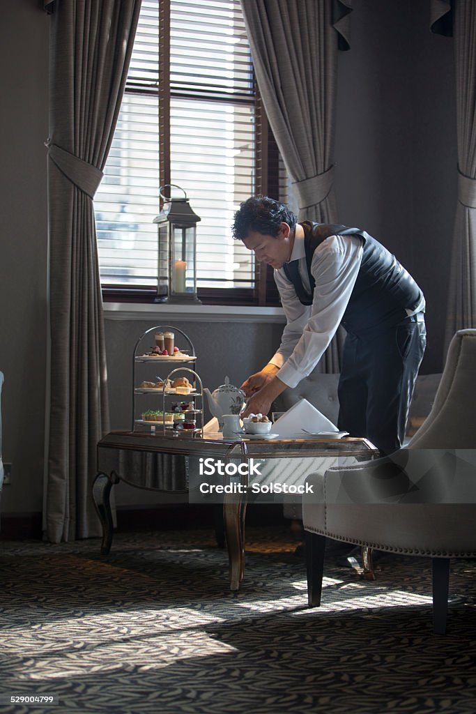 Setting Up Afternoon Tea Shot of a waiter setting up an afternoon tea arrangement. Hotel Stock Photo
