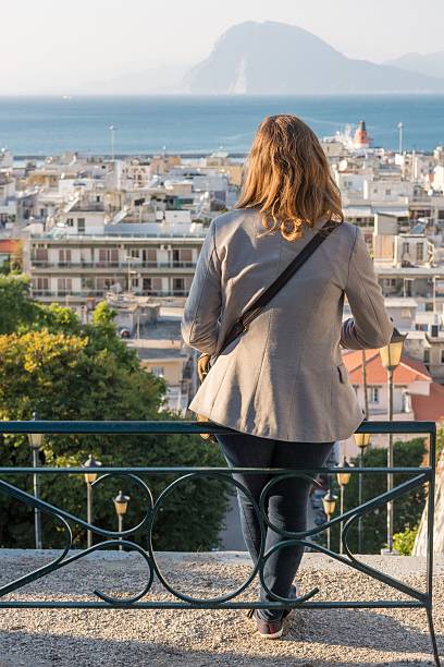 istock Girl sitting on a bench above a city 529005605