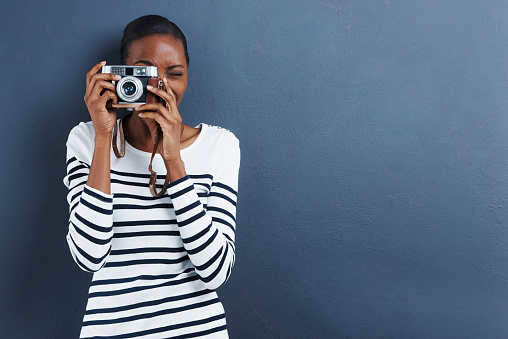 Shot of an attractive young woman taking a photo with a vintage camera