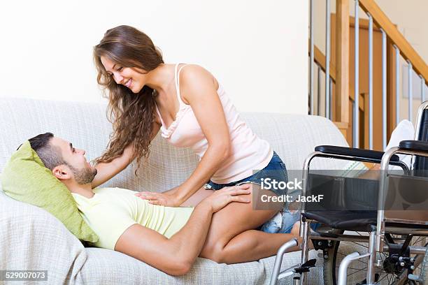 Couple On Couch Near Wheelchair Stock Photo - Download Image Now - Adult, Apartment, Cheerful