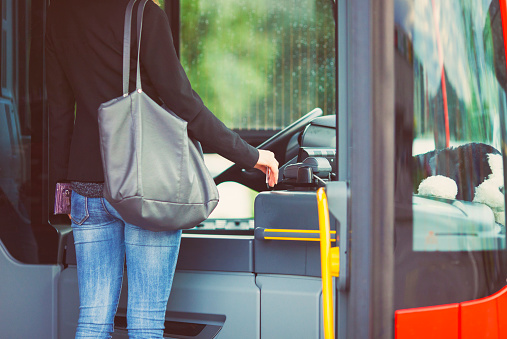 Young female passenger paying the bus fare with a contacless smart card