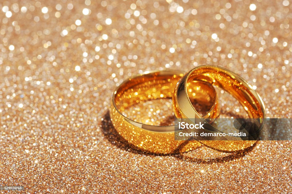 Two rings Two golden rings on gold glitter background Backgrounds Stock Photo