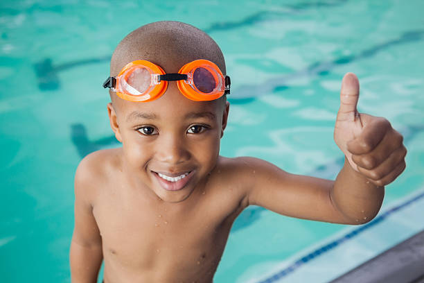 милый маленький мальчик, давая пальцы вверх на бассейн - swimming child swimming pool indoors стоковые фото и изображения