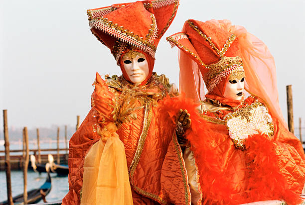 casal no carnaval de veneza com laranja costumes e máscaras - entertainment holidays and celebrations venice italy performer imagens e fotografias de stock