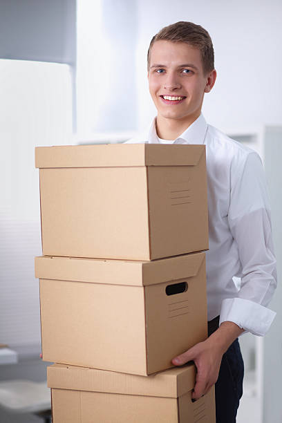 istock Young Man holding a stack of cardboard boxes standing in 529047411