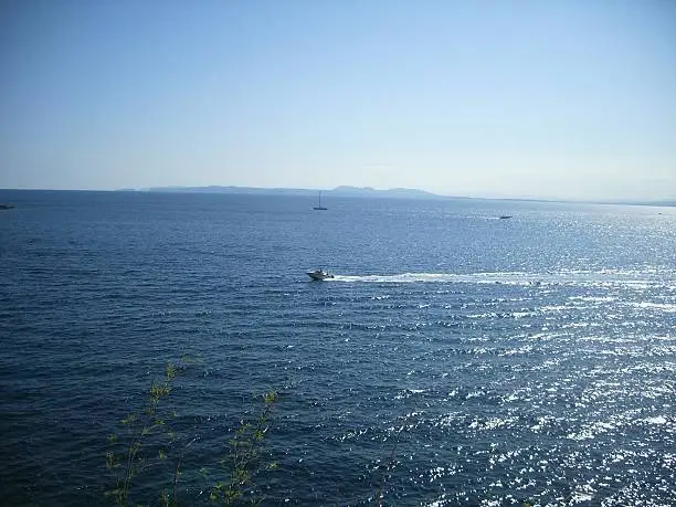 A motorboat drives at the costa brava over the very blue Mediterranean under a blue sky in summer