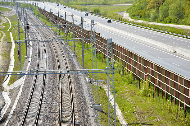 istock Modern railway route and highway separated by fence in countryside 529049962