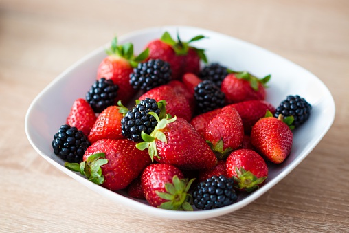 White plate full of strawberries and blackberries. Healthy spring breakfast