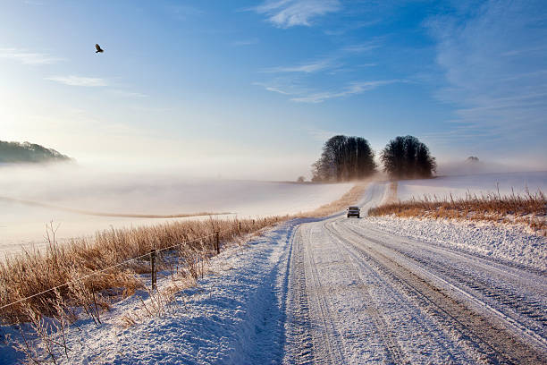 Car driving in a wintry rural landscape