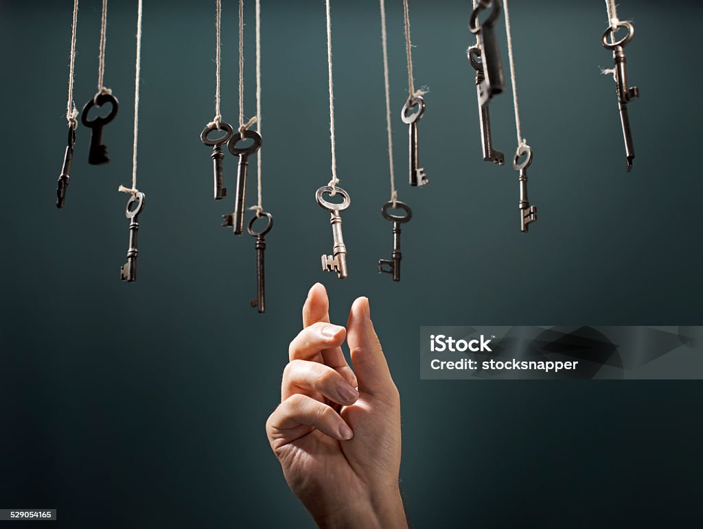 The Right Key Hand choosing a hanging key amongst other ones. Key Stock Photo