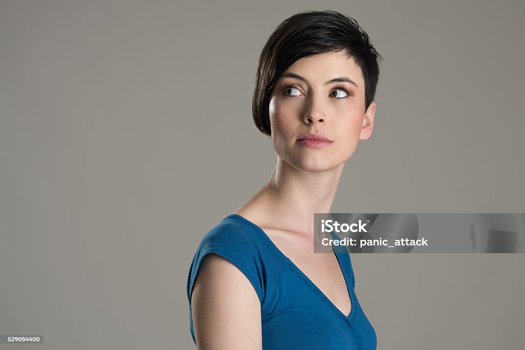 Portrait of short hair beauty looking back over the shoulder Studio shot of short hair beauty model looking back over the shoulder with copyspace over gray background Women Stock Photo