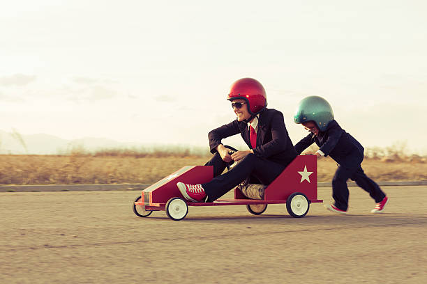 молодой мальчик с деловая женщина с игрушка гоночный автомобиль - car child teamwork sports race стоковые фото и изображения