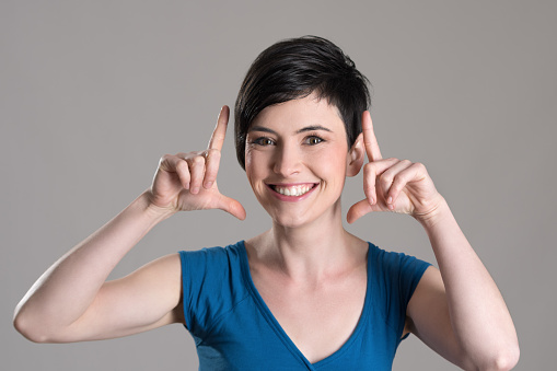 Studio portrait of young short hair beauty with finger frame gesture over gray background