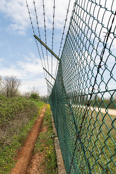 istock Mesh fence topped with barbed wire. 529054752