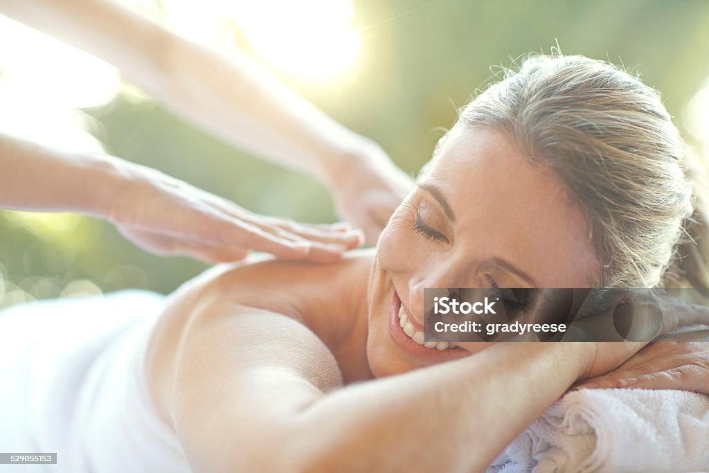 That feels amazing... Shot of an attractive mature woman enjoying a massage at a day spa Massaging Stock Photo