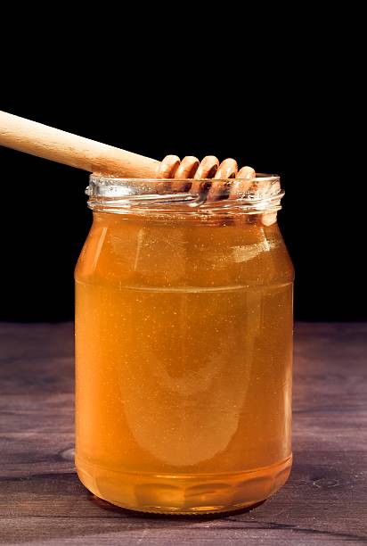 istock opened honey jar on wood table and black background 529057622