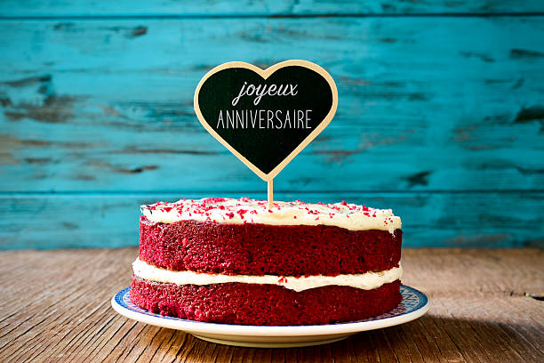 text joyeux anniversaire, happy birthday in french a red velvet cake with a heart-shaped chalkboard with the text joyeux anniversaire, happy birthday in french, on a rustic wooden table anniversaire stock pictures, royalty-free photos & images