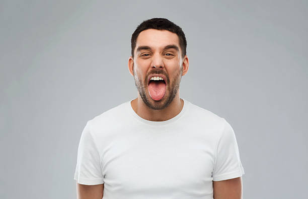 istock man showing his tongue over gray background 529058570