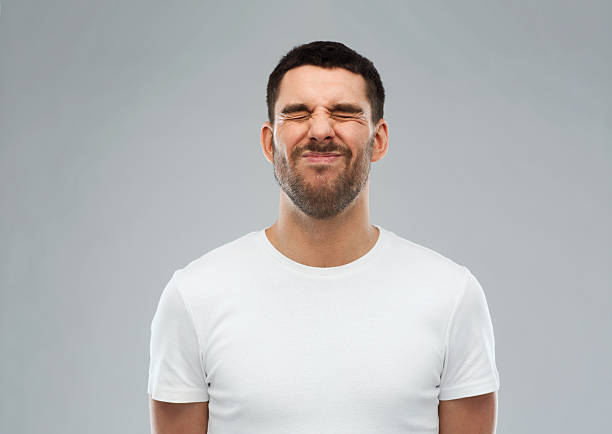 man wrying over gray background emotion and people concept - young wrying man over gray background grimacing stock pictures, royalty-free photos & images